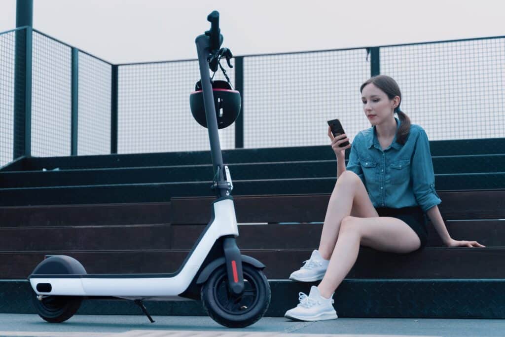 a woman sitting on steps next to a scooter