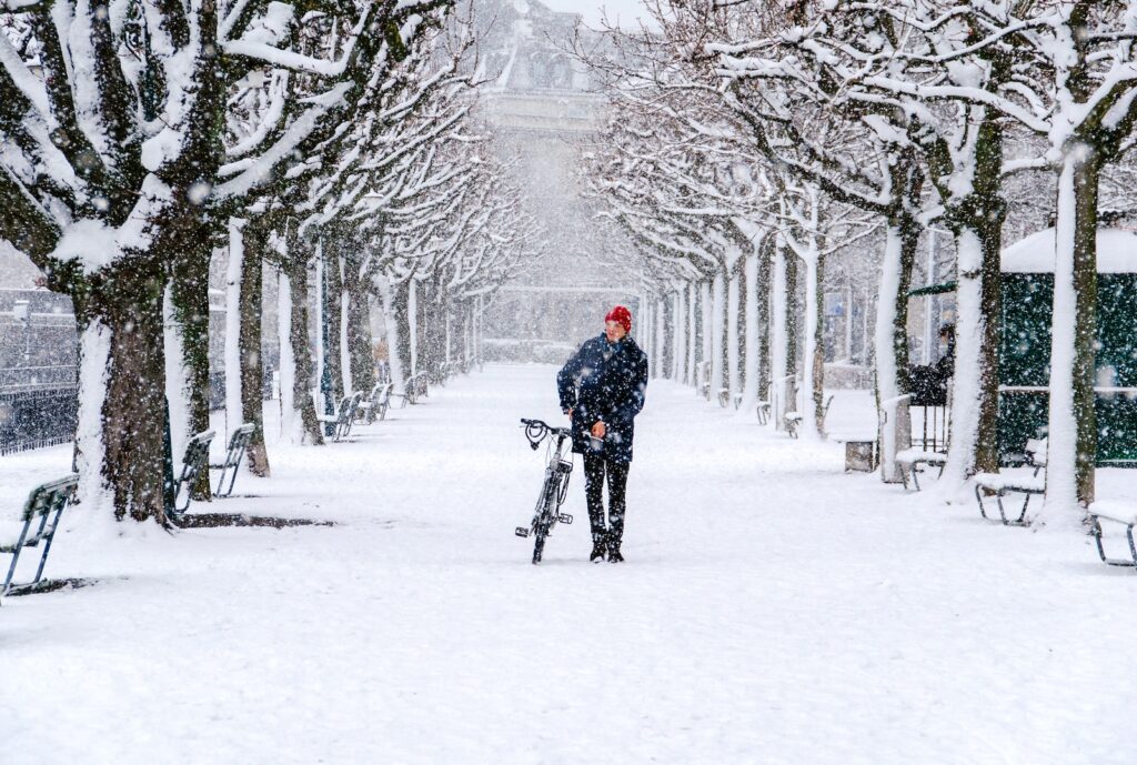 man walking with his bicycle during snow