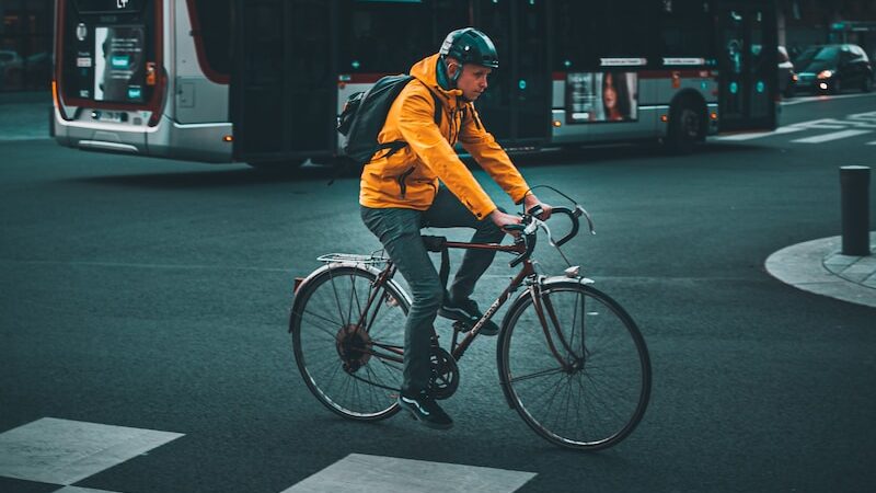 a man riding a bike down a street next to a bus