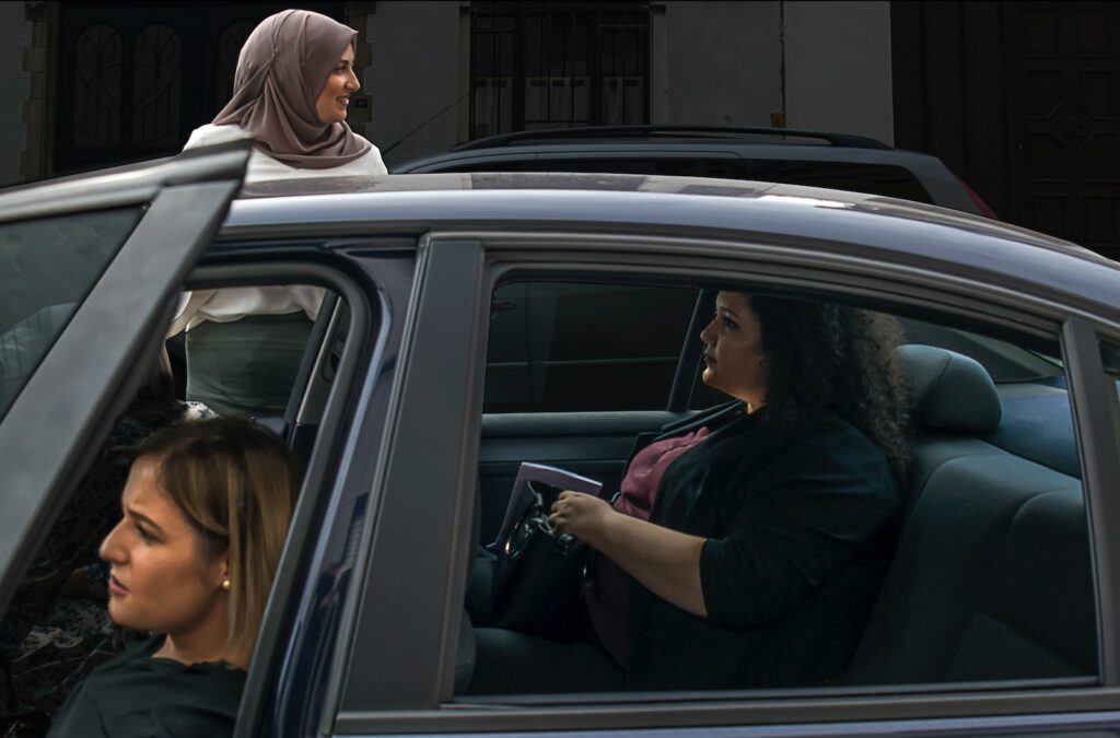 two woman inside vehicle beside woman on the outside wearing brown hijab headscarf during daytime